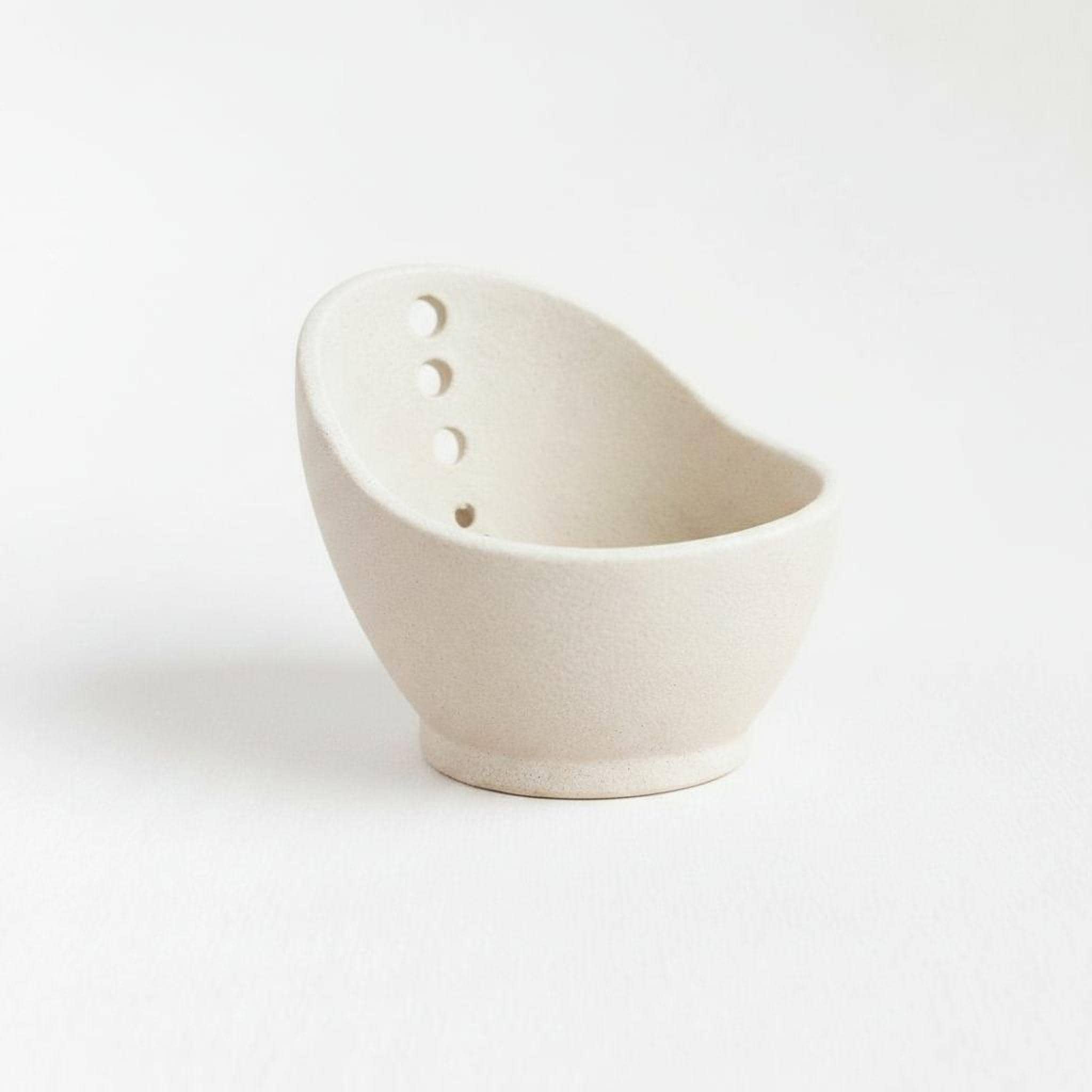 A simple, white ceramic bowl with three holes on the side.