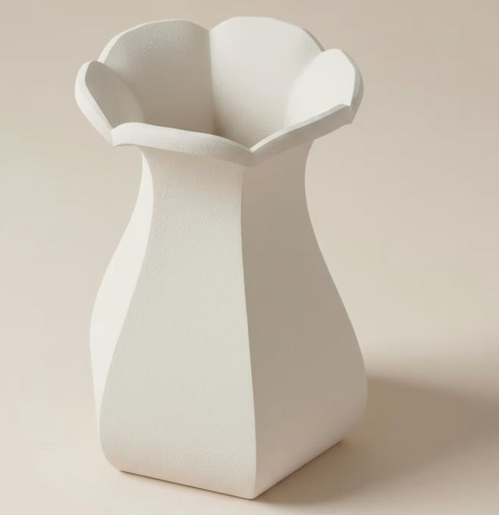 A white, geometric vase with a pointed top and flared bottom, standing alone against a light background.