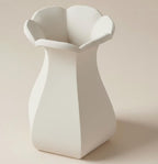 A white, geometric vase with a pointed top and flared bottom, standing alone against a light background.