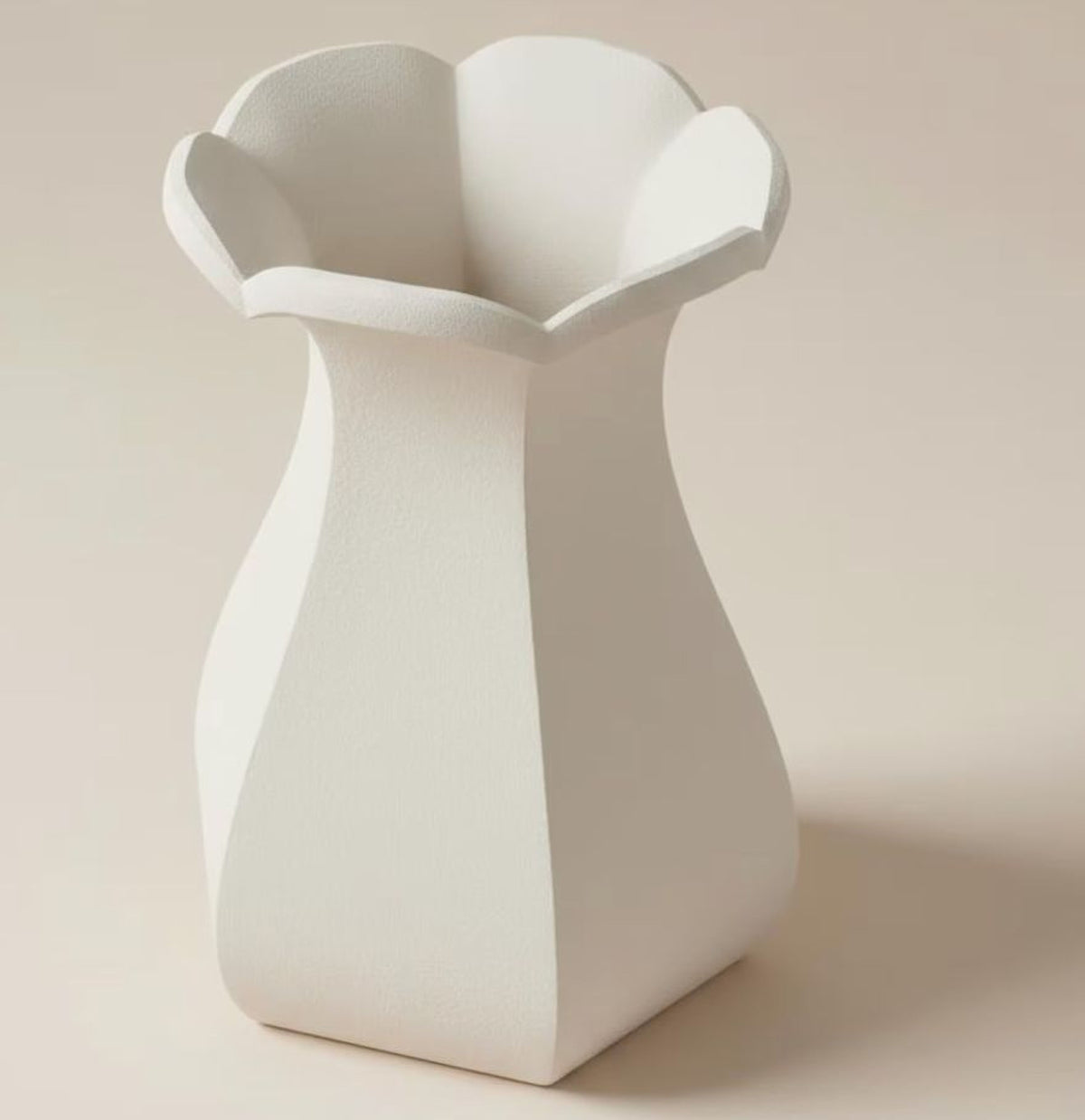 A white, geometric vase with a pointed top and flared bottom, standing alone against a light background.