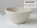 a white ceramic bowl with a hole in the center, placed on a white surface.