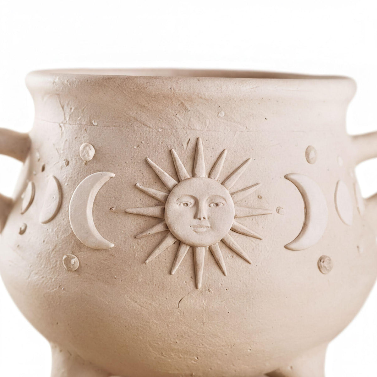 A close-up image of a ceramic pot with a sun and moon design on it.