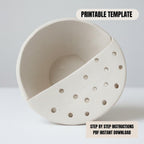 a white ceramic bowl with holes in it, placed on a white surface.