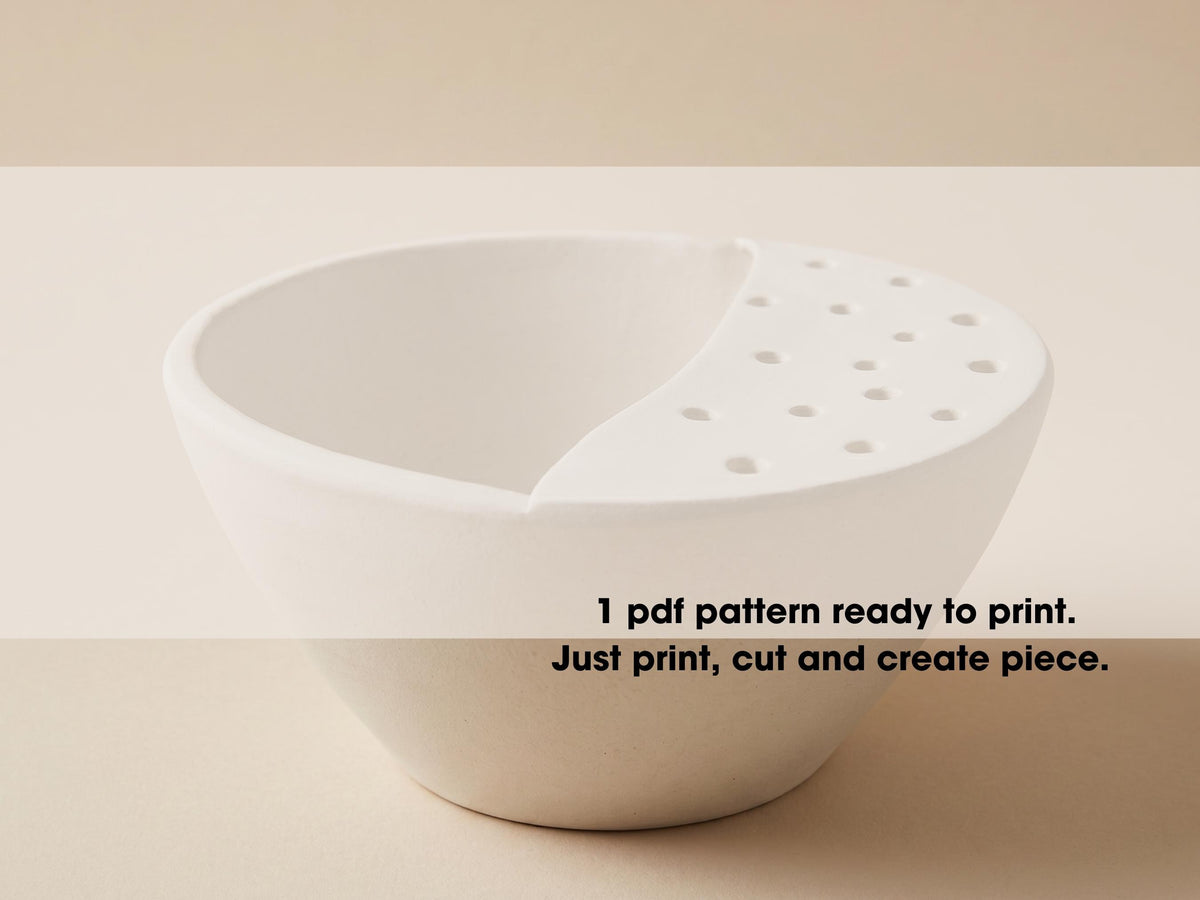 A white ceramic bowl with a hole in the center, sitting on a plain background.