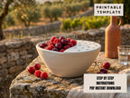 a bowl filled with fresh raspberries, placed on a stone surface, with a glass of water and a bottle nearby.