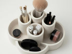 A white makeup tray containing various makeup items such as brushes, compact powder, and lipsticks.