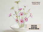 a white bowl filled with a variety of pink and white flowers, including daisies and other types of flowers, placed on a white surface.