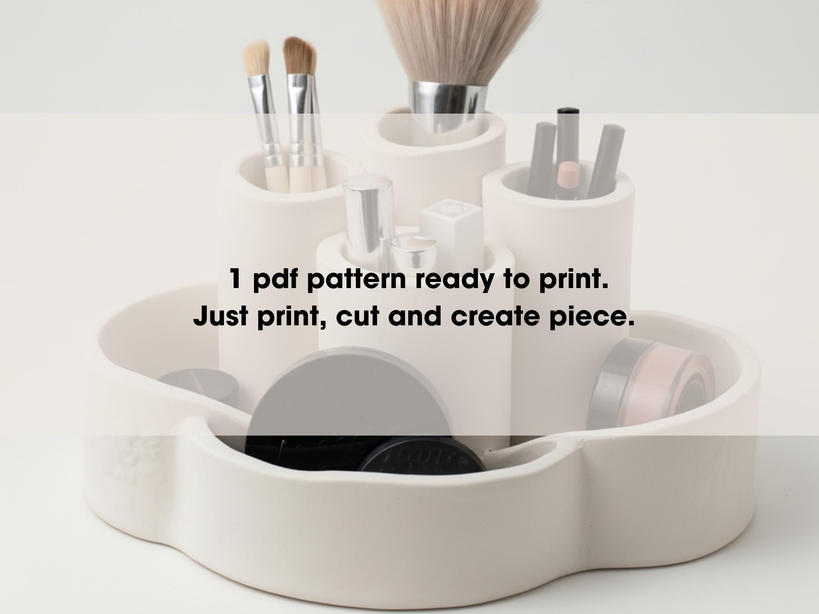 A white ceramic makeup holder containing various makeup brushes and containers, along with a text overlay that reads "1 pdf pattern ready to print. Just print, cut and create piece."