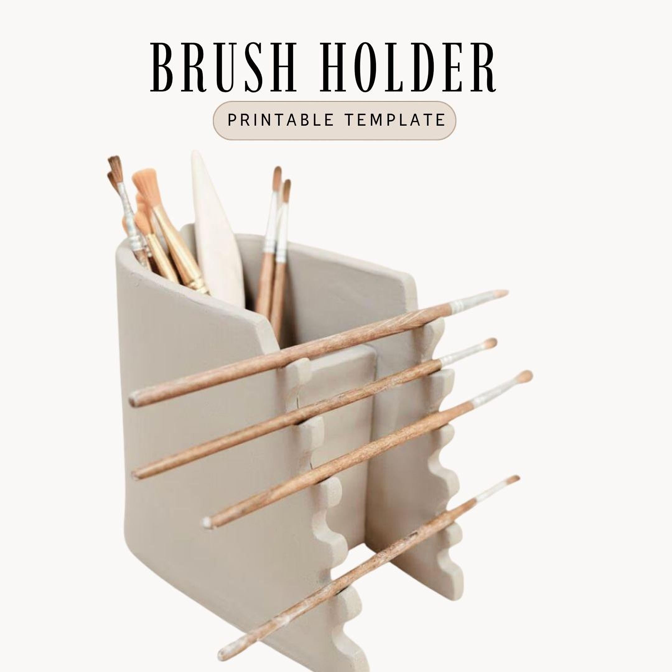 A white ceramic brush holder with multiple wooden paintbrushes inside it.