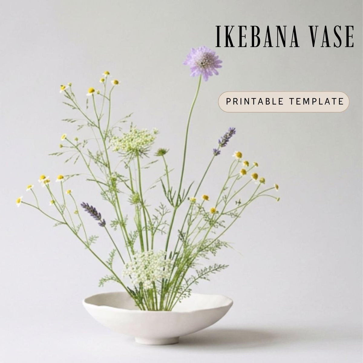 A white Ikebana vase filled with a variety of flowers, including daisies and lavender, against a plain white background.