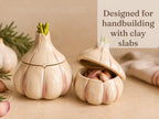 two ceramic garlic bulbs with clay slabs, one with the lid open and the other with the lid closed.