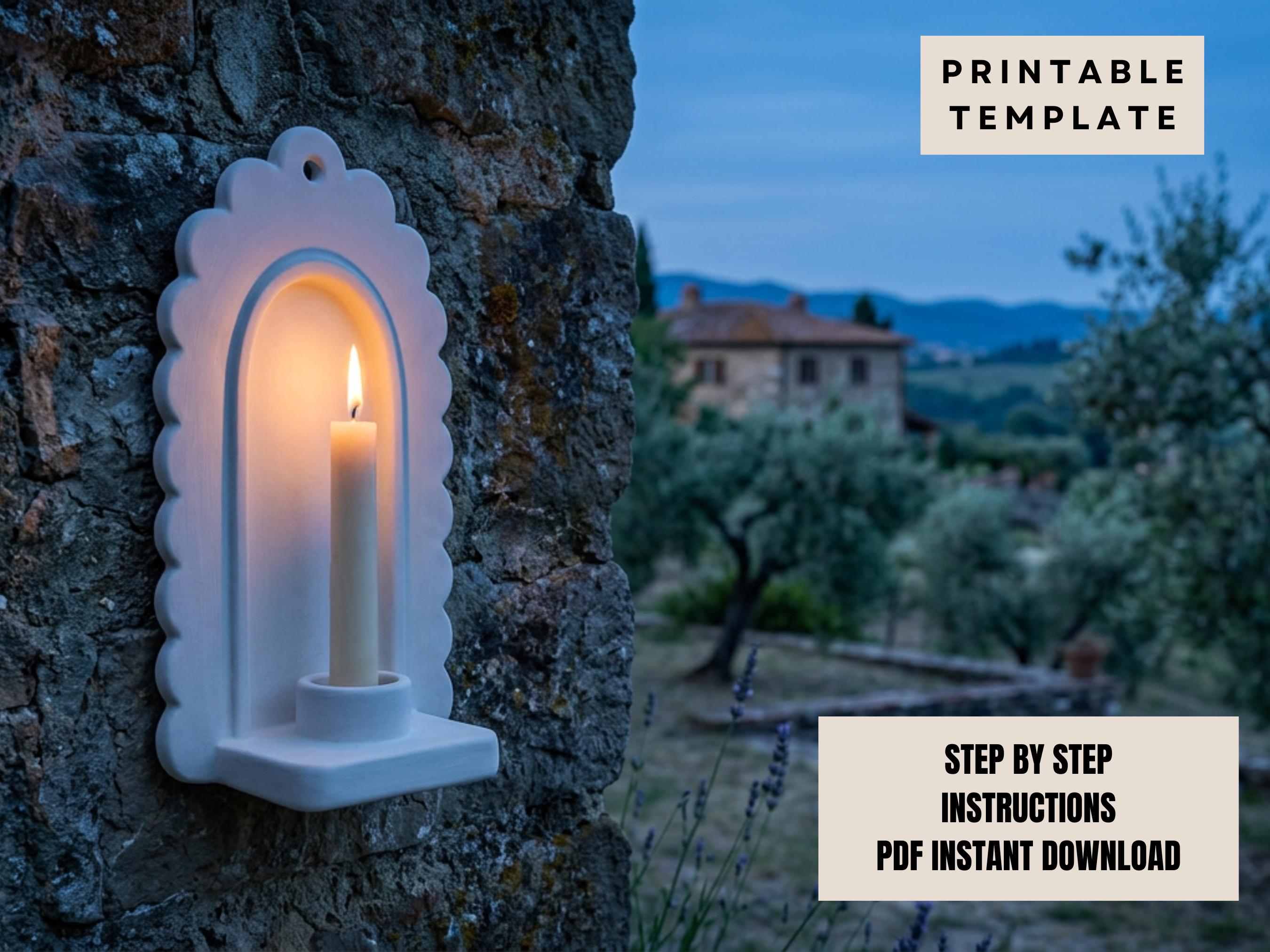 a white candle holder mounted on a stone wall, with a lit candle inside. In the background, there is a house surrounded by trees, creating a serene and peaceful atmosphere.