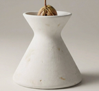 A white ceramic vase with a small plant growing in it, placed on a plain surface.