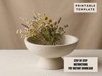 a white ceramic bowl filled with a bouquet of dried flowers, placed on a white surface.