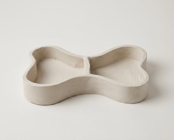 A simple, white ceramic bowl or dish with a curved, organic shape.