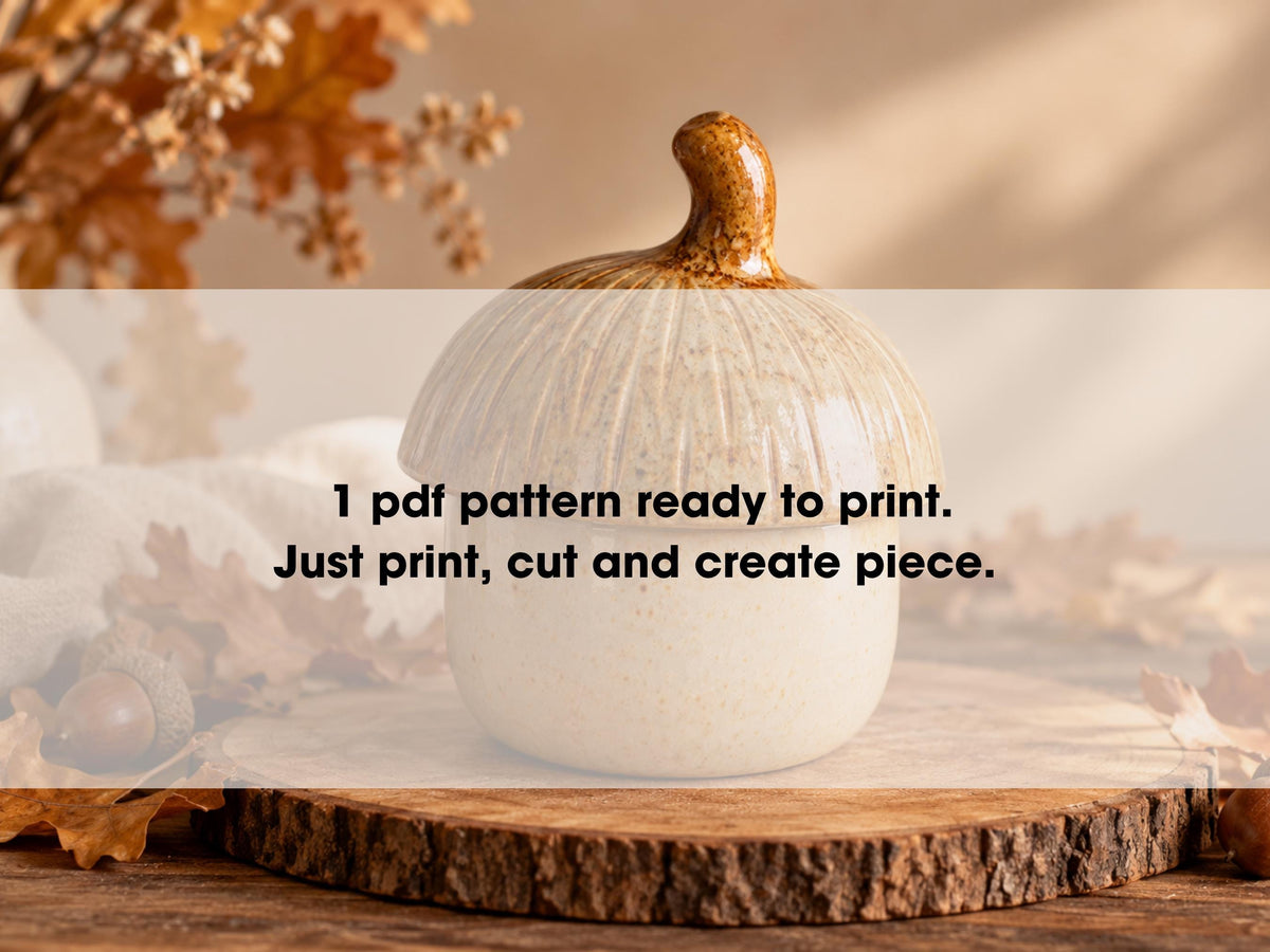 A white ceramic pumpkin with a brown stem sits on a wooden surface, surrounded by autumn leaves.