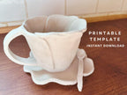 Handmade ceramic mug shaped like a flower blossom, with a matching wavy-edged saucer and small spoon. The mug has a textured surface and a natural clay finish, displayed on a wooden countertop. Text overlay reads "Blossom Mug – Step by Step Instructions, PDF Instant Download.