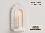 a white candle holder with a lit candle inside, set against a plain white background.