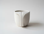 A white ceramic mug with a unique, abstract design resembling a whale's head or trunk.