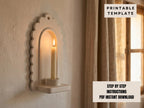 a white candle holder mounted on a wall, with a lit candle inside.