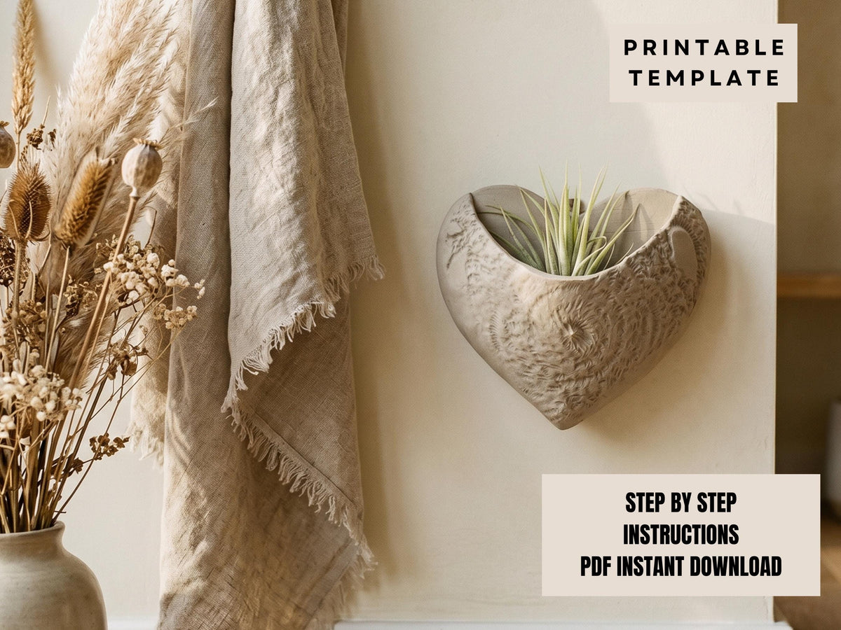 a heart-shaped planter with a plant growing in it, placed on a wall next to a beige shawl and a vase of dried flowers.
